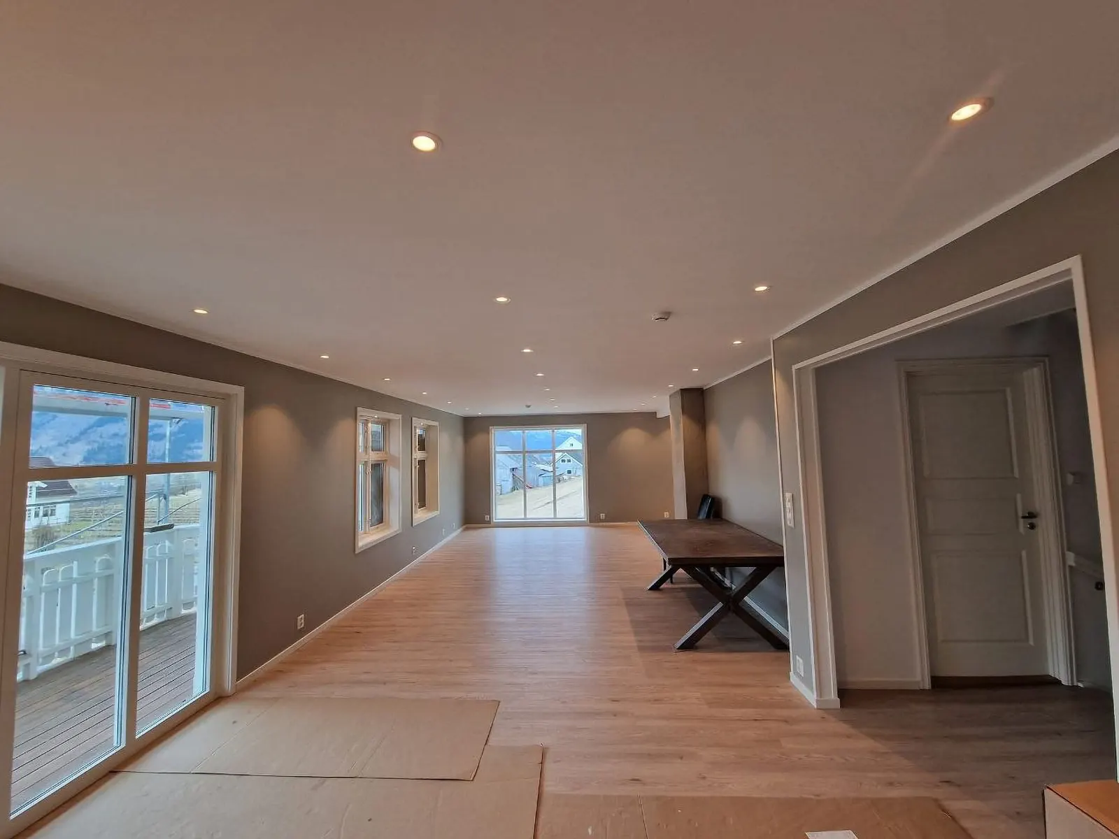 Ferdig oppusset langt oppholdsrom med lyse flater og downlights